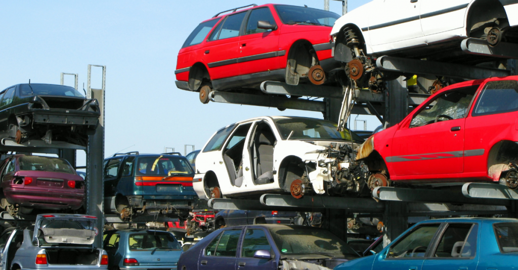 Scrapped cars with parts missing stacked up on racks outside