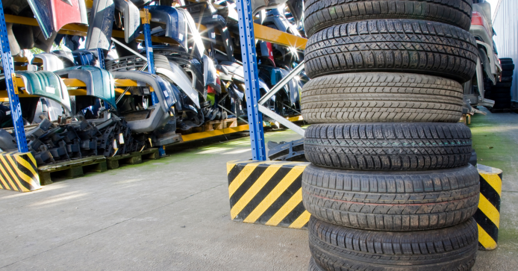 Stack of used tyres and car parts on racks