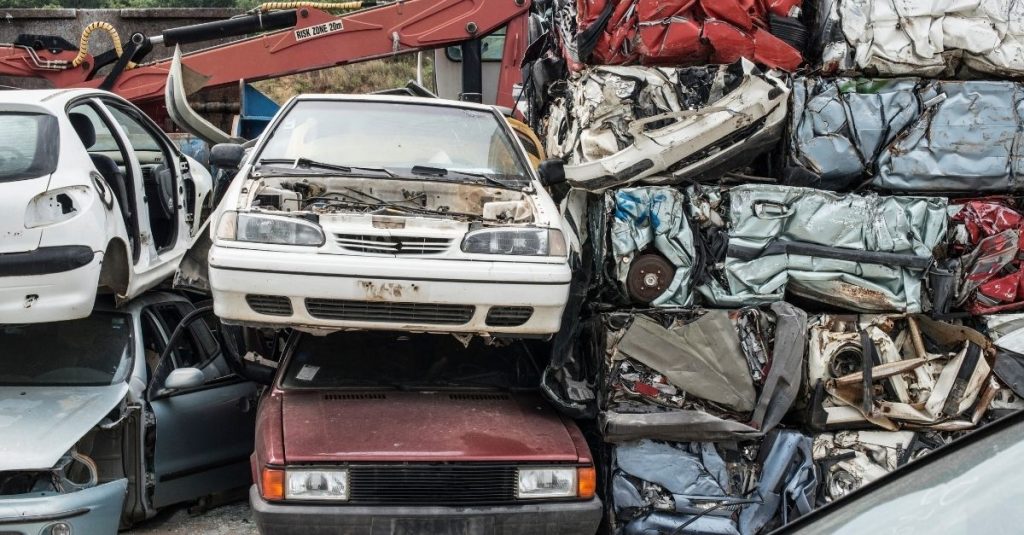 Scrap cars stacked on top of each other beside a tower of crushed cars.