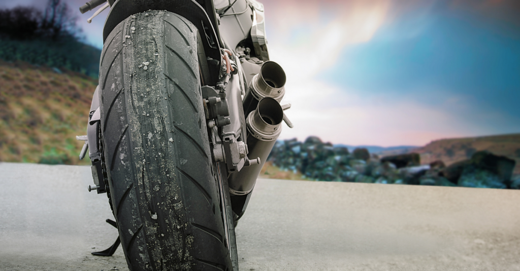 Close up shot of the back end of a motorbike parked in a rural hilly area.
